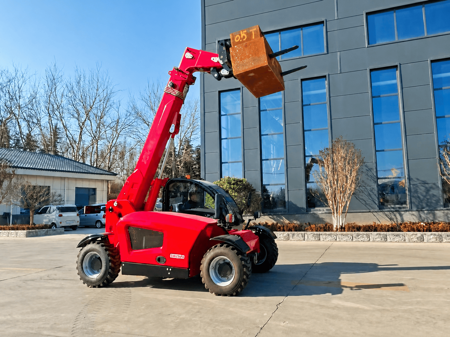 Telehandler lifting a pallet to a high scaffold on a construction site -- full machine including extended boom visible