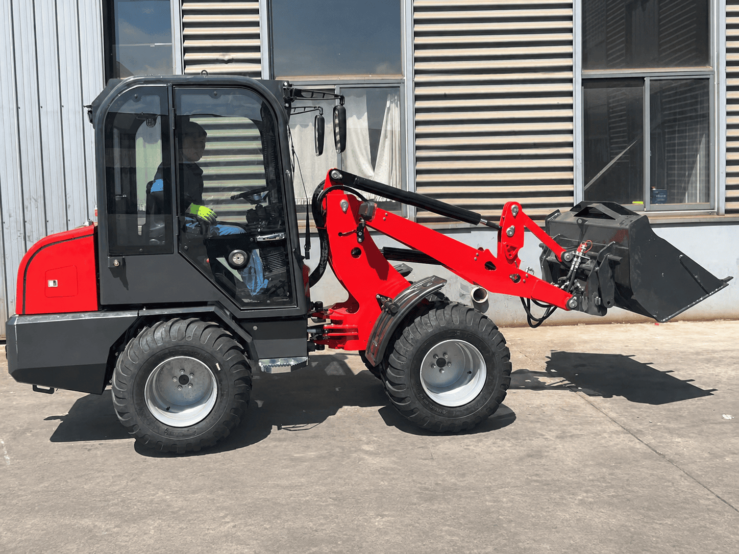 Wheel loader moving aggregate material in a yard -- full machine including bucket and wheels visible